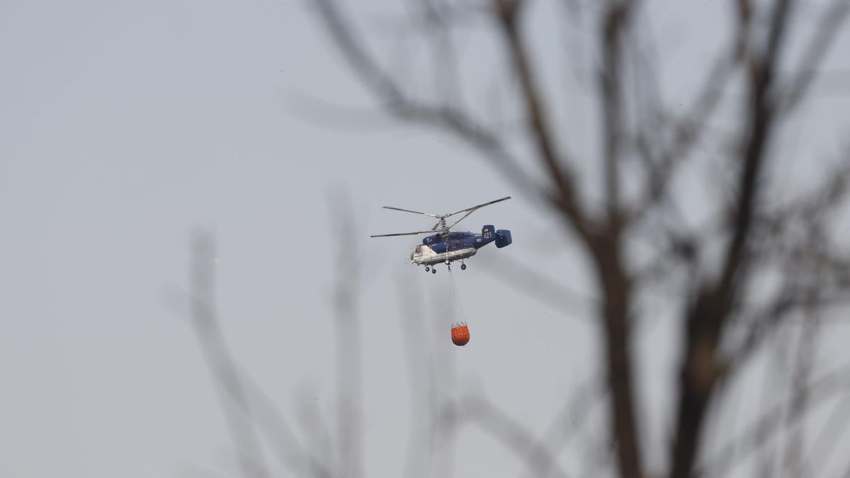 Un helicóptero lleva agua en el incendio de Sierra Bermeja.