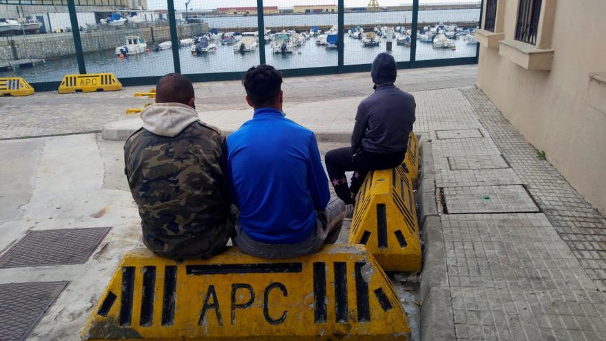 Menores migrantes sentados esperando en un puerto.