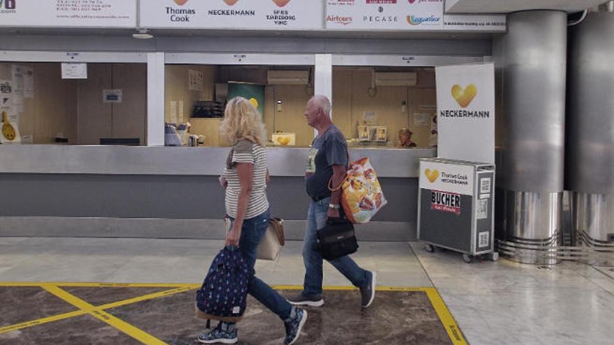 Dos turistas, ayer, pasando frente a las oficinas de Thomas Cook y de sus divisiones continental y escandinava en Tenerife Sur.