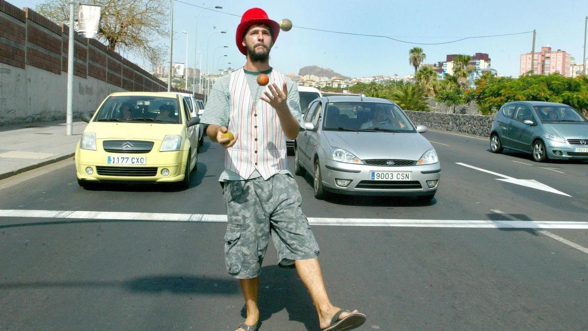 Un ciudadano realiza malabares en un semáforo de Santa Cruz de Tenerife, mientras los coches están parados