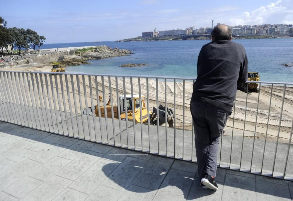 Las máquinas extienden la arena en la playa de Riazor.