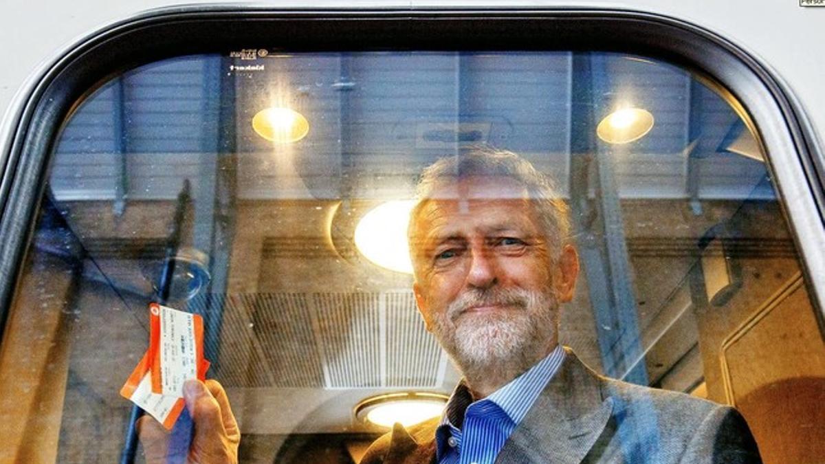 Jeremy Corbyn fotografiado en el interior de un vagón de tren sujetando dos billetes.
