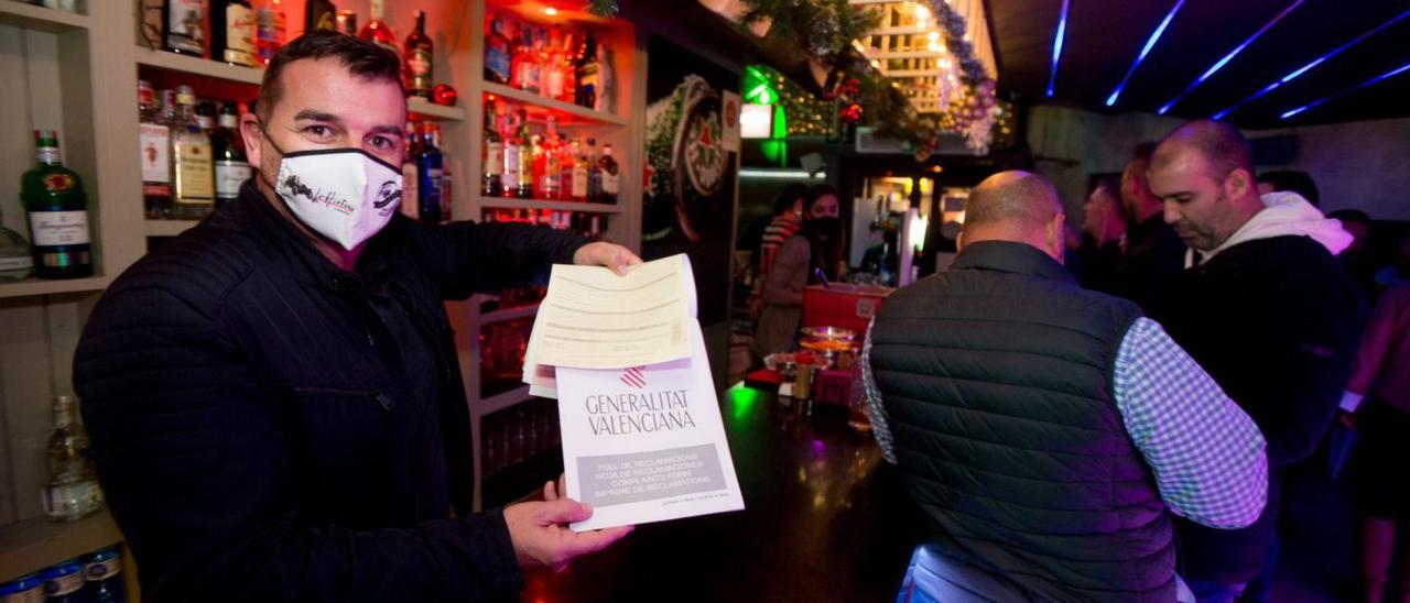 El propietario de un café pub del centro de Alicante muestra hojas de reclamaciones rellenas. | JOSE NAVARRO