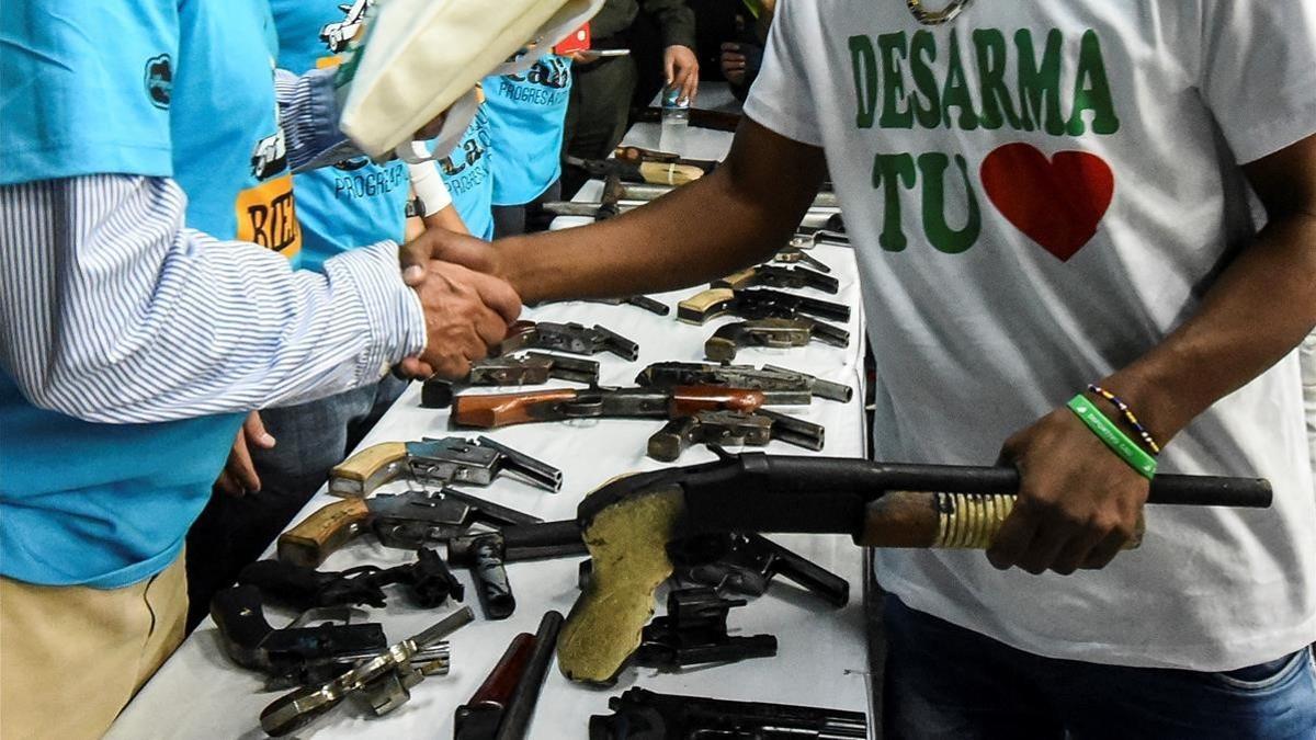 Un miembro de una banda entrega su arma en una ceremonia en Cali, el pasado julio.