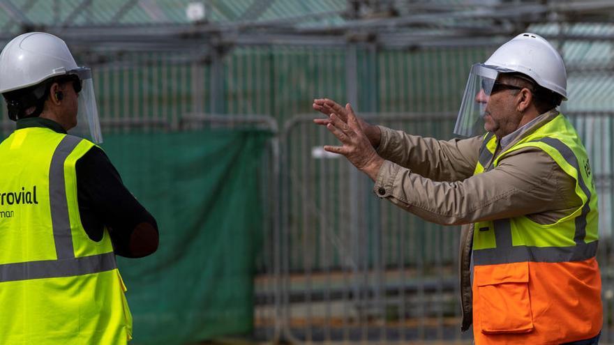 Dos tÃ©cnicos con mÃ¡scaras protectoras conversan a pie de obra.