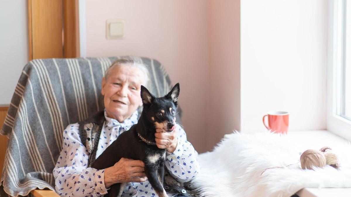 Una anciana con su mascota en su casa.