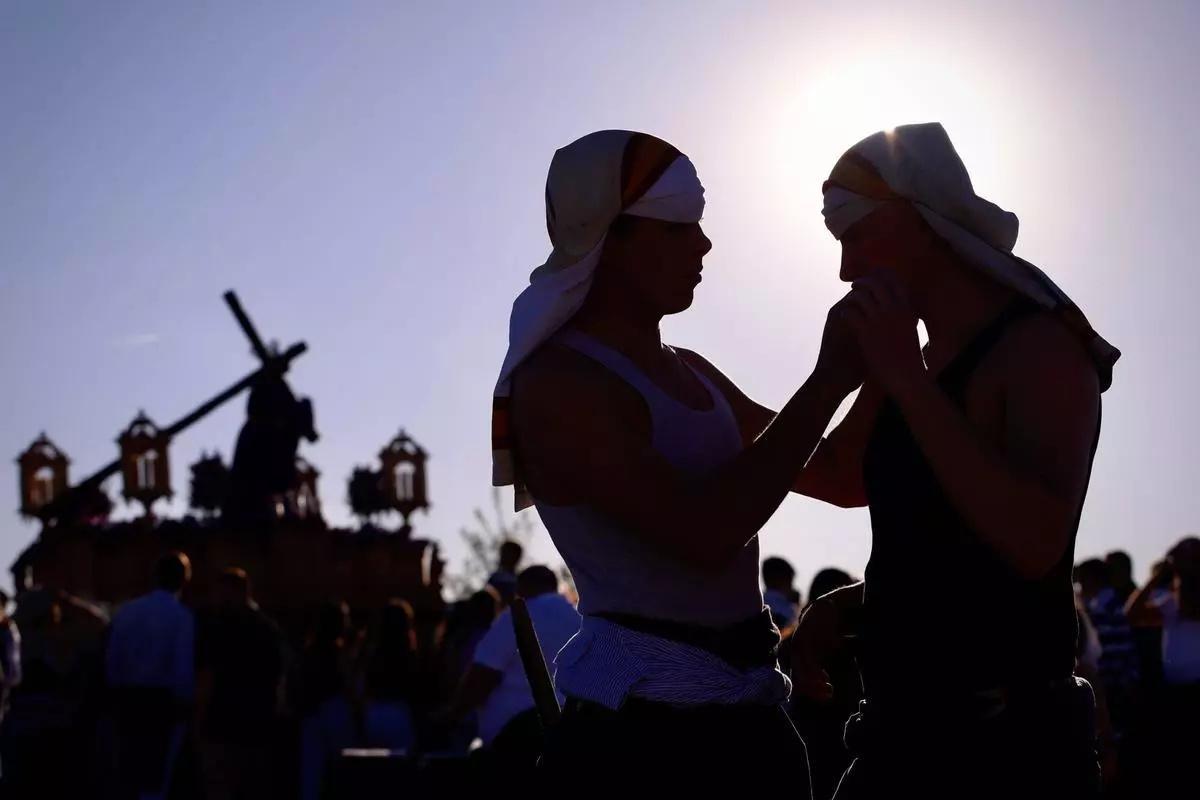 Costaleros de Jesús de la Compasión se ajustan su costal al paso de la hermandad por las calles del Higuerón.
