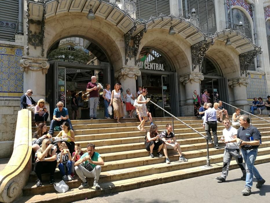 Turistas y usuarios sentados en la escalera del Mercat