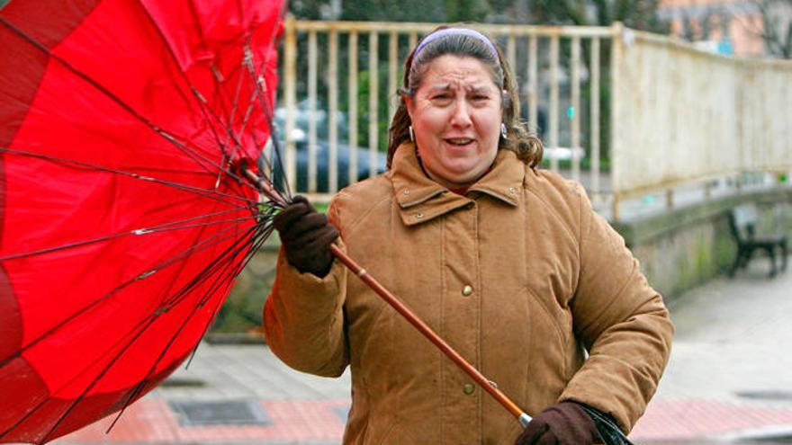 Una mujer sujeta su paragüas en pleno temporal. // Marta G. Brea