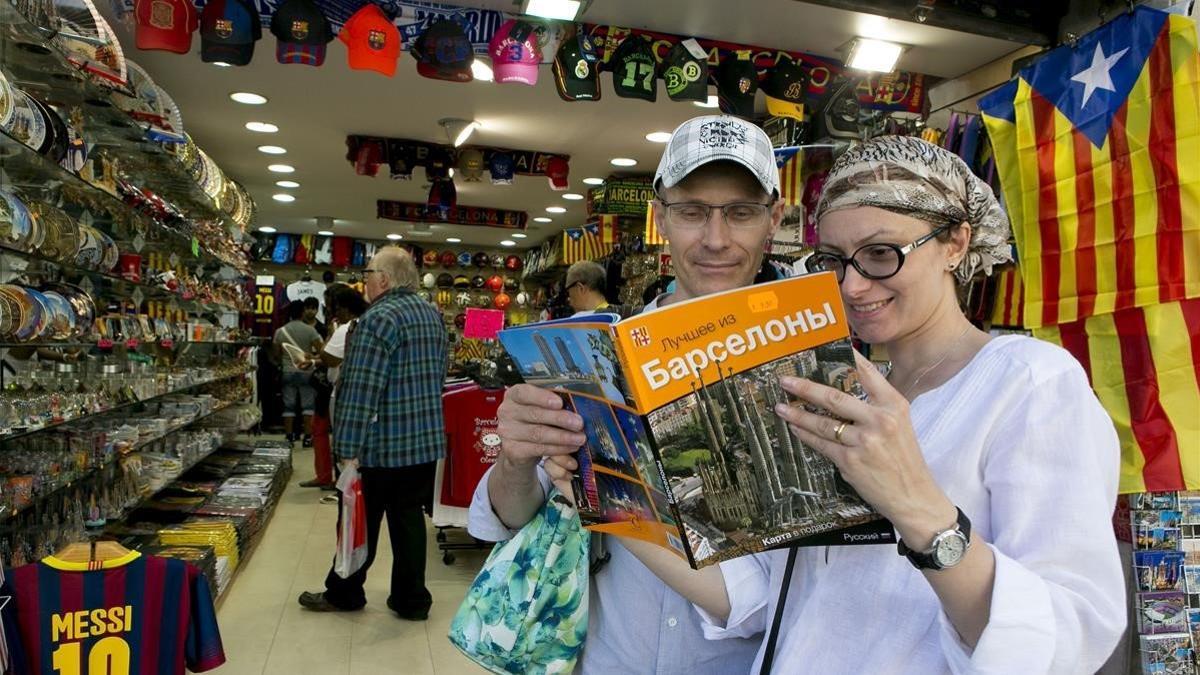 Dos turistas rusos consultan una guía de Barcelona en su idioma al salir de una tienda de suvenirs de la zona de Sagrada Família, en septiembre del 2014