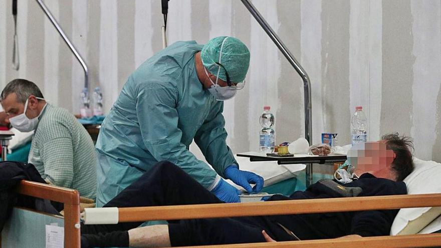 Un sanitario atiende a un paciente en una instalación provisional al lado del hospital de Brescia.