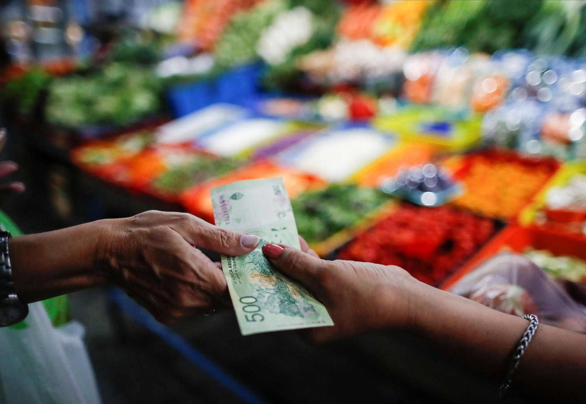 Una compradora paga en una tienda de frutas y verduras en un mercado de Buenos Aires.