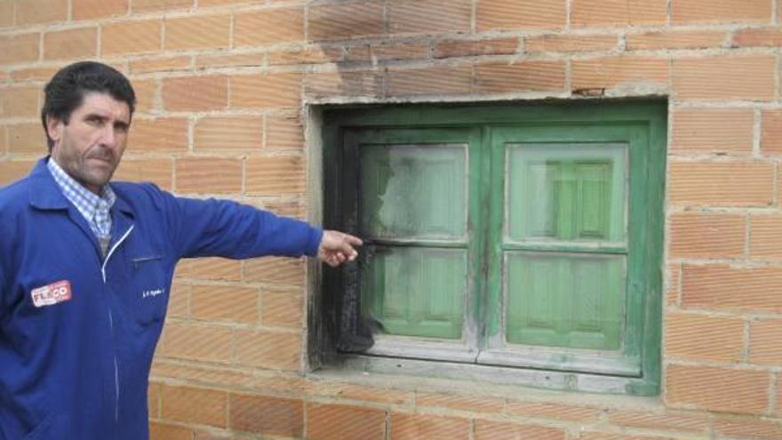 Tomás Fresno, alcalde de Pueblica, señala el estado en que quedó la ventana de la casa de su madre tras el incendio.