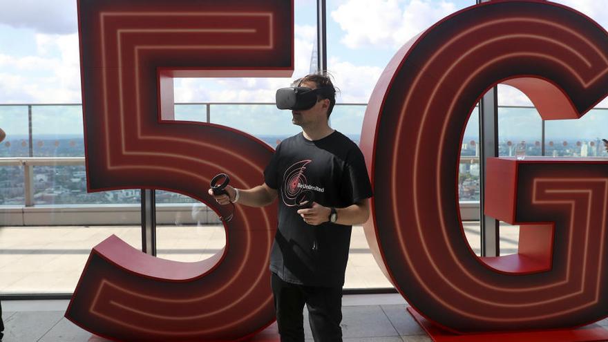 Un hombre, frente a un logo de 5G