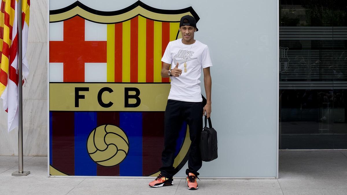 Neymar posa junto al escudo blaugrana de las oficinas del club en su primera aparición en Barcelona.