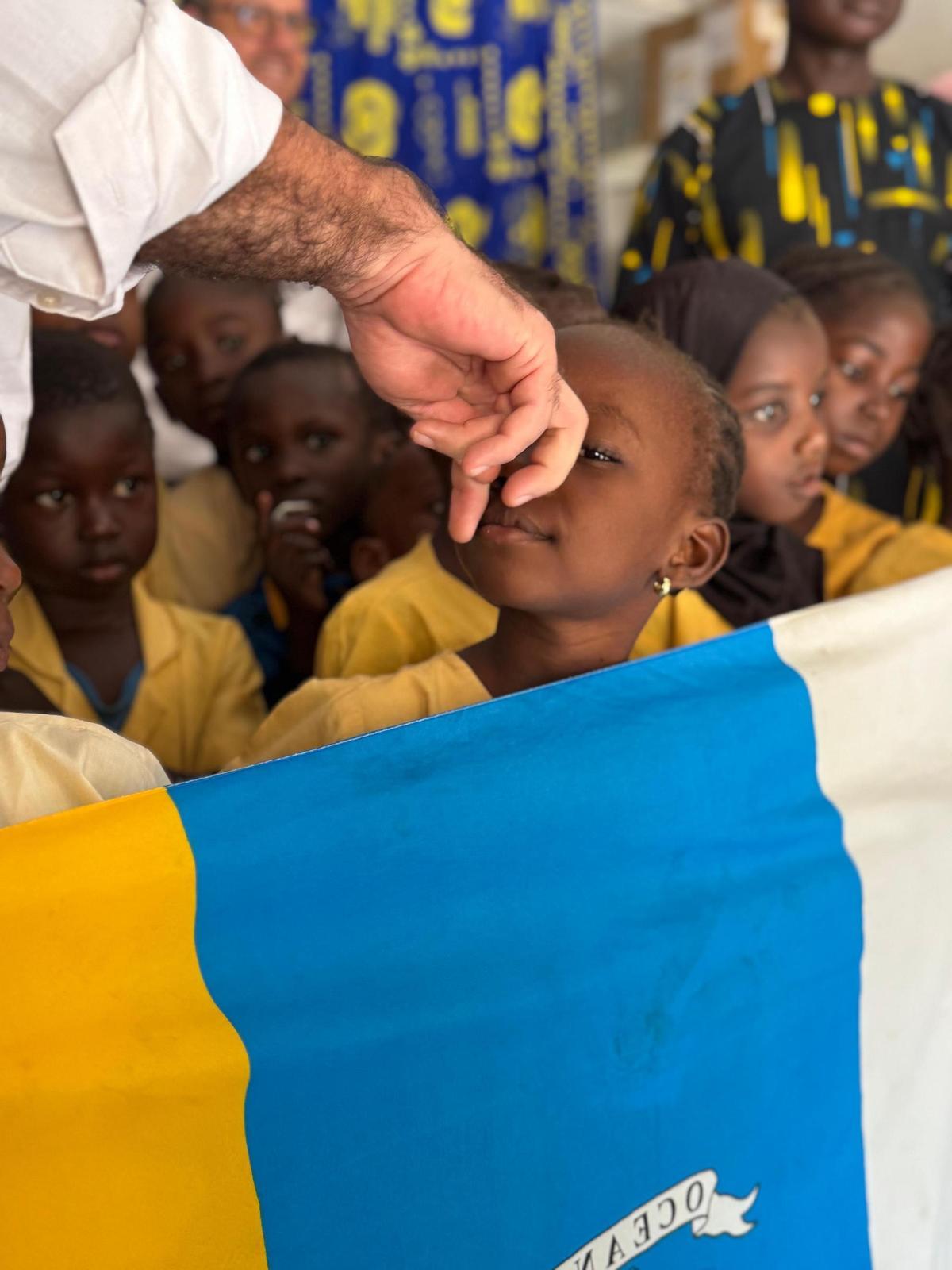 Una alumna del Canarias Lamin School sostiene una bandera canaria.