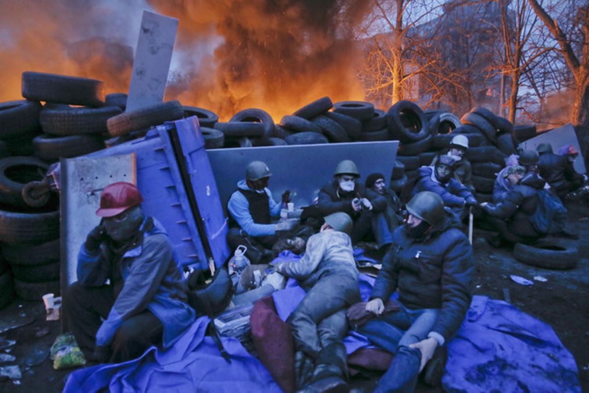 Varios activistas descansan tras las barricadas en llamas.