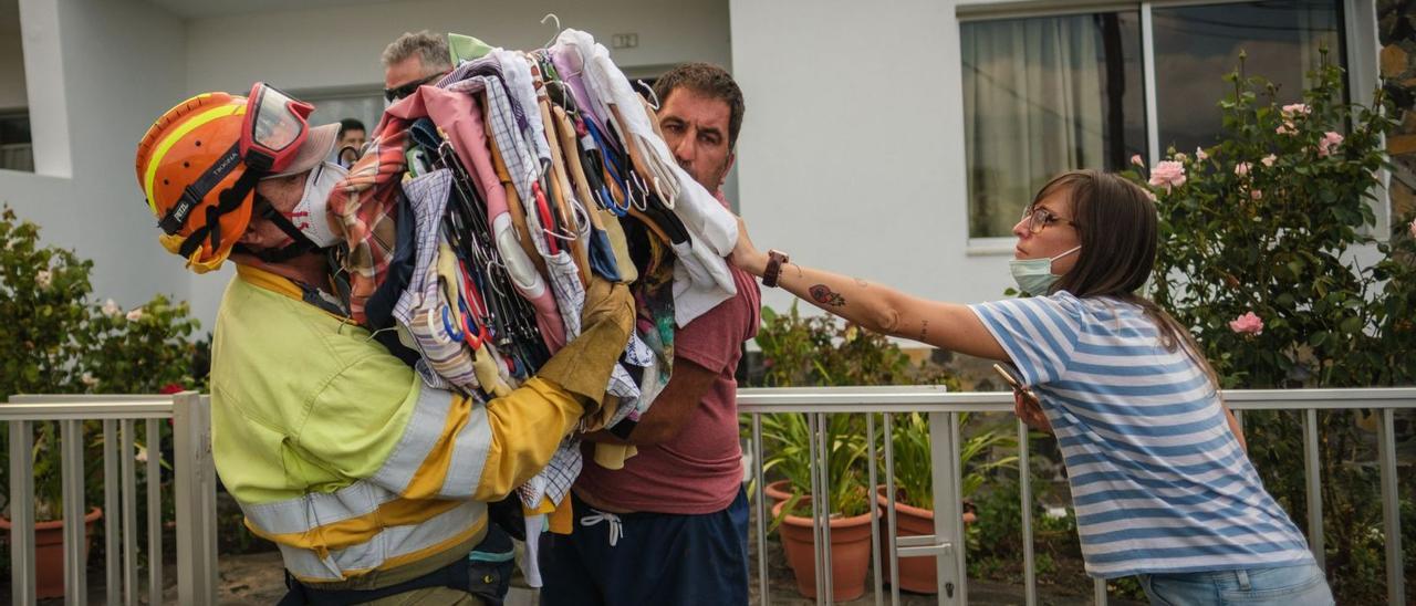 Un bombero ayuda a una familia palmera a extraer todos los enseres posibles de su hogar en los primeros días tras la erupción. | | ANDRÉS GUTIÉRREZ