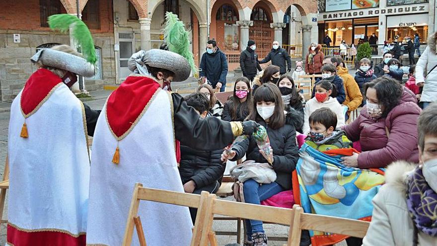 Los pajes reales reparten cucuruchos con golosinas, mientras los niños combaten el frío con mantas. | E. P.