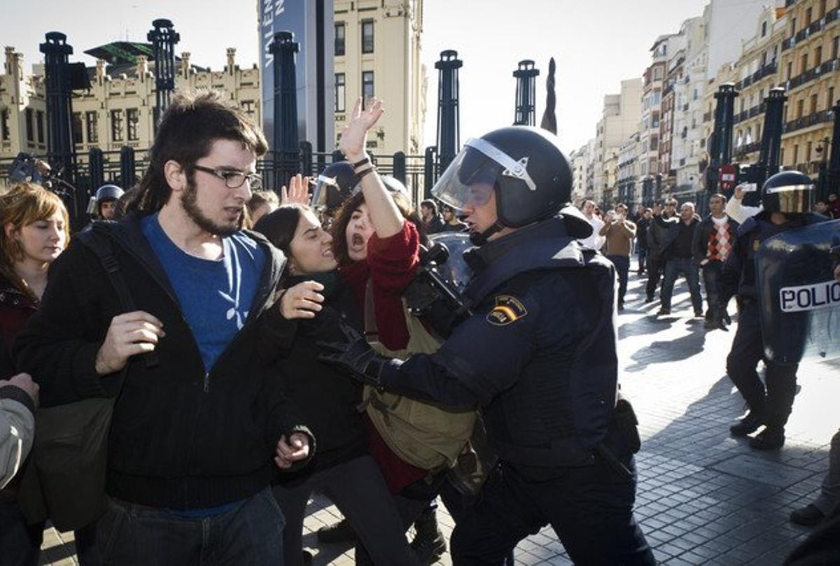 Un agent dels Antiavalots aparta un grup de joves davant de l’estació de trens.