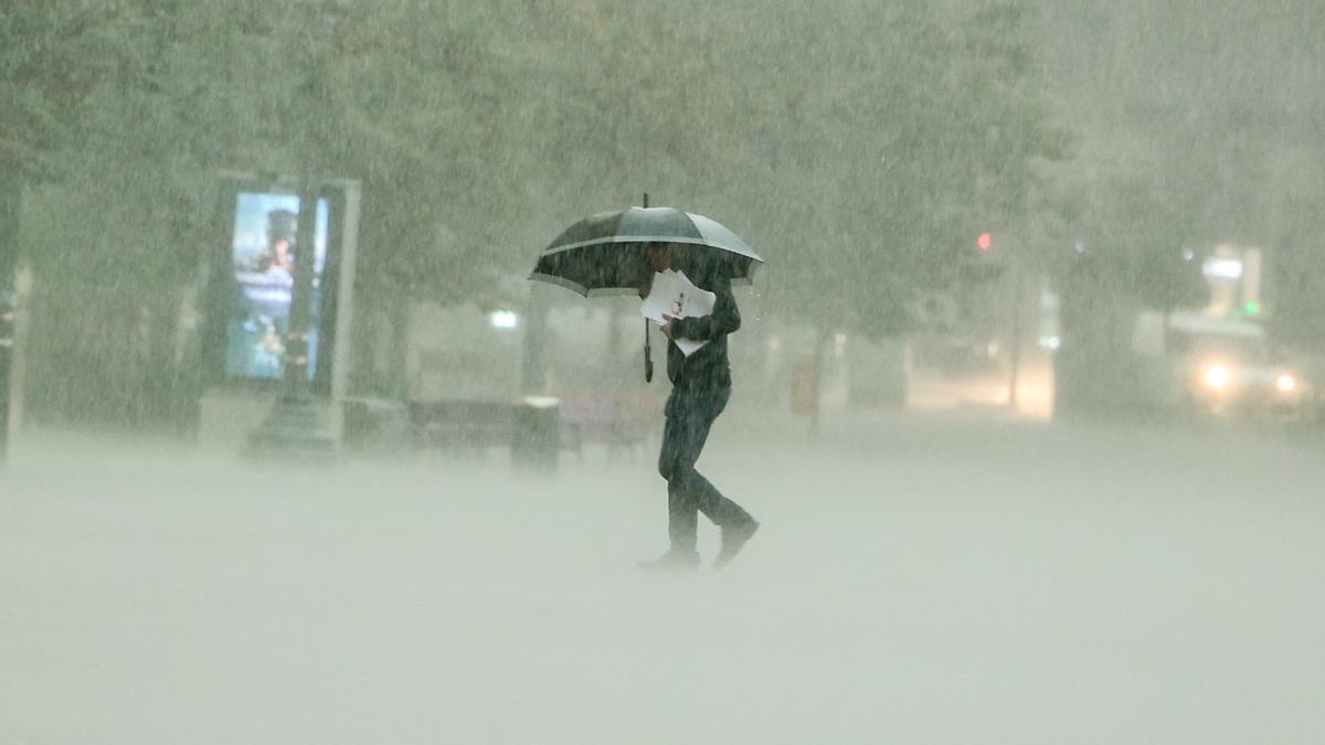 Una persona s&#039;aixopluga sota un paraigües