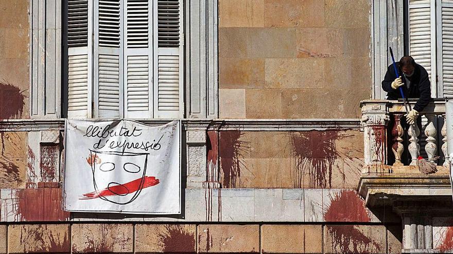 Un treballador neteja les pintades de la façana de la Generalitat.