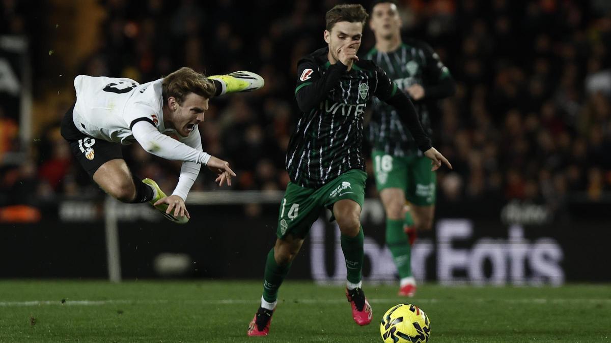 Febas conduce el balón durante el Valencia-Elche, ante el salto de un rival
