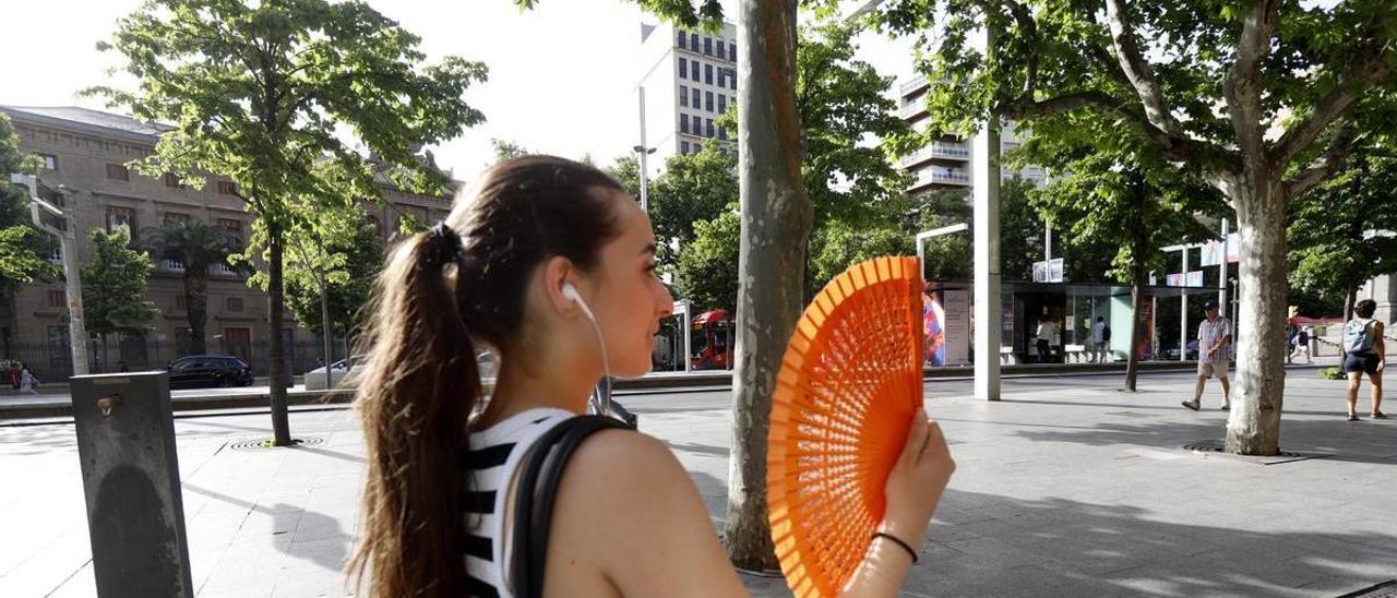 Una joven zaragozana se abanica bajo las altas temperaturas registradas estos días en Zaragoza.