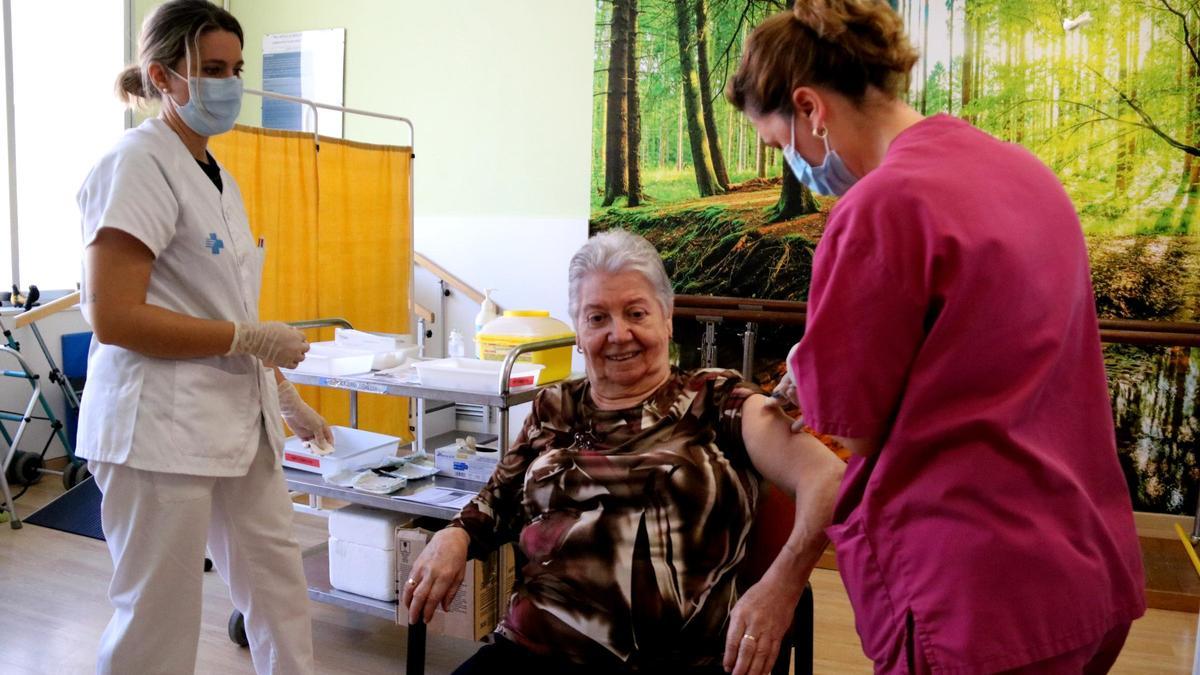 Una usuària de la residència Sant Miquel Arcàngel de Tortosa, rebent la vacuna de la covid assistida per dues infermeres.