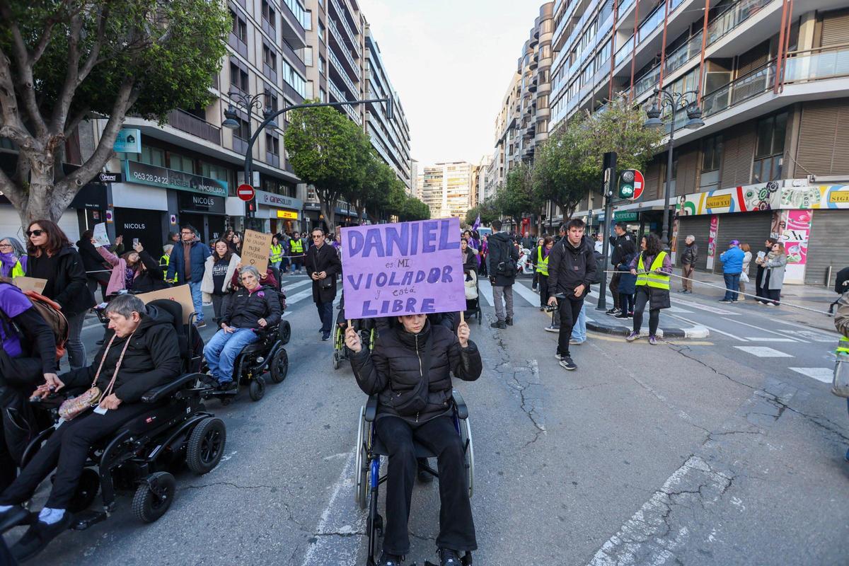 Una mujer en silla de ruedas sujeta su pancarta: "Daniel es mi violador y está libre"