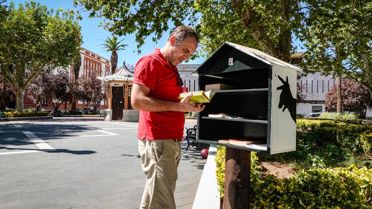 Un usuario hojea uno de los libros de la caseta del paseo de San Francisco de Badajoz.