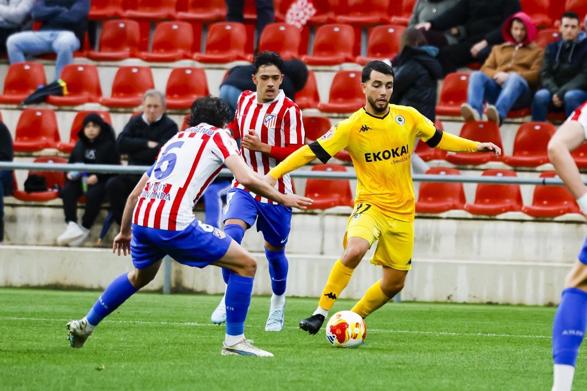 Mehdi Puch esconde la pelota ante dos defensores del Atlético Madrileño en Alcalá de Henares.