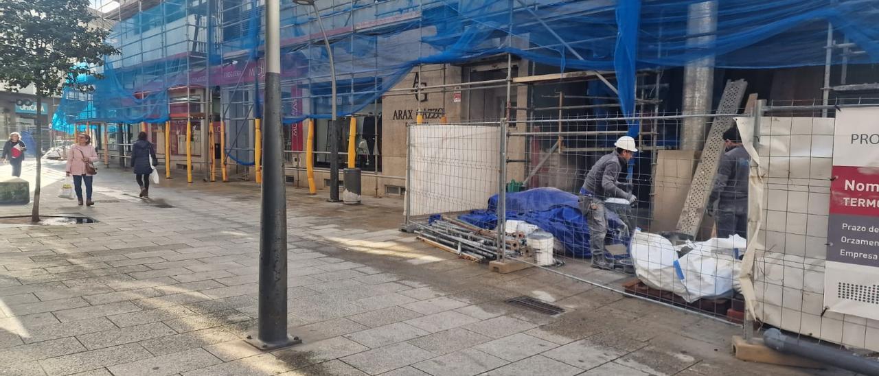 Dos operarios cortando piedra ante uno de los comercios.