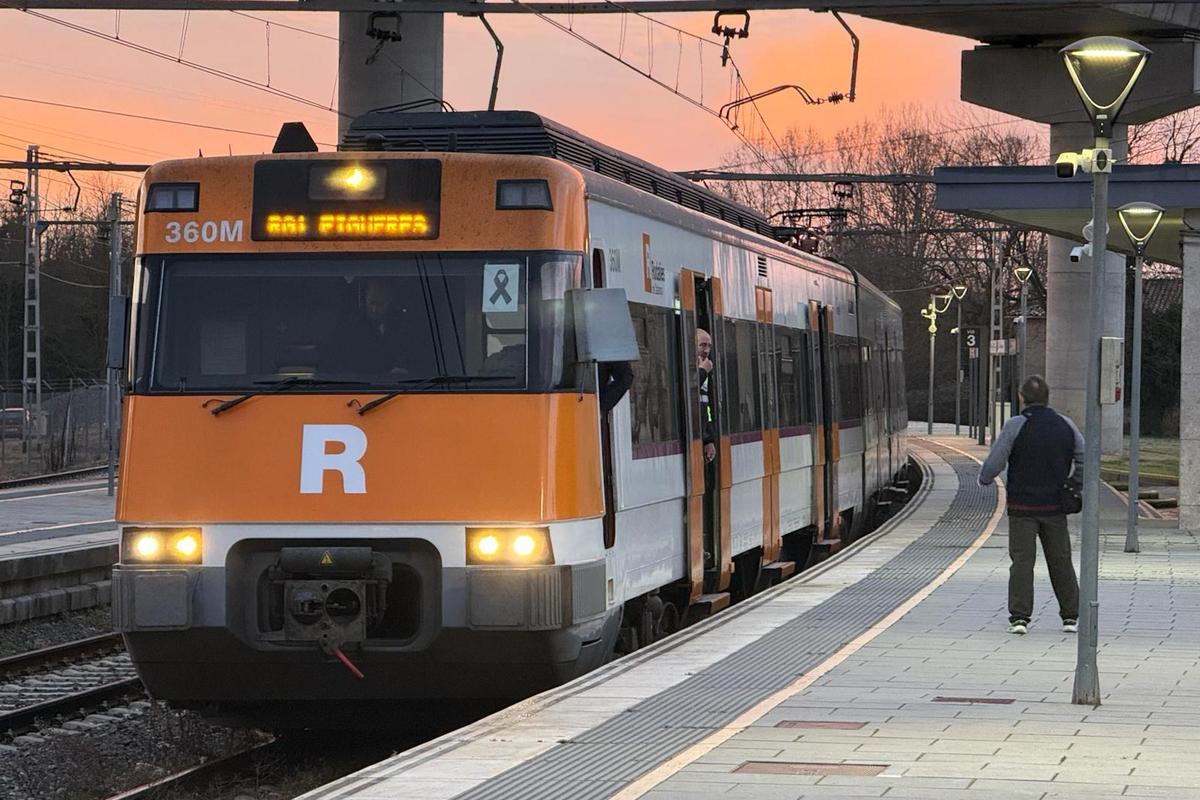 Un usuari de Rodalies parla amb un treballador d'un tren a l'andana de Maçanet