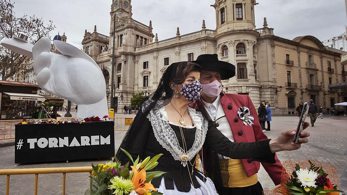 Una pareja de falleros se hace una foto junto al pebetero. En su base se acumulan los ramos de flores. | GERMÁN CABALLERO