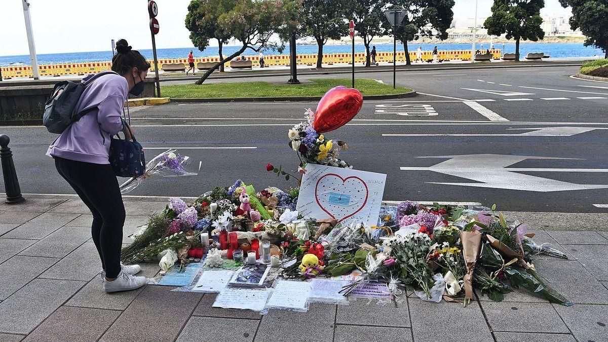 Una joven deposita unas flores en el improvisado homenaje a Samuel, en la avenida de Buenos Aires, con el paseo marítimo.