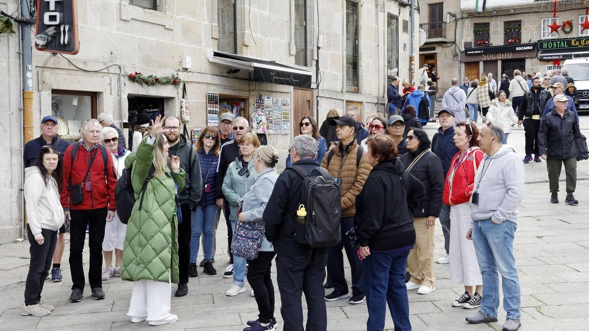 Turistas atienden las explicaciones de un guía en una ruta por el Casco Vello.