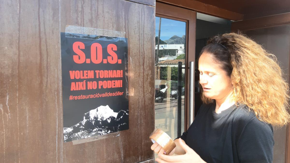 Una mujer cuelga el cartel de la campaÃ±a en un establecimiento de SÃ³ller.