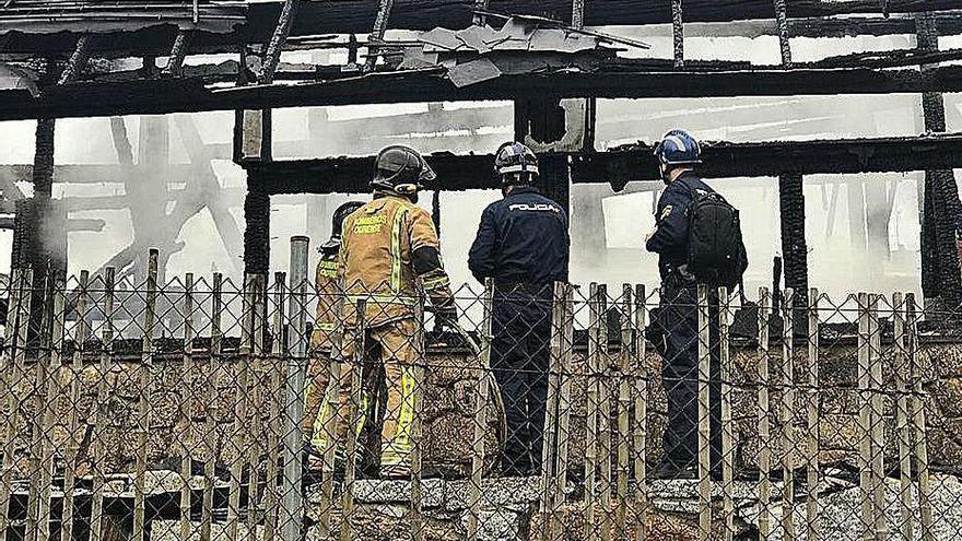 Policías y bomberos inspeccionando los daños, tras el fuego.