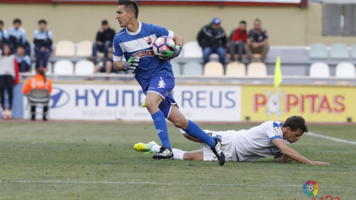 El portero del Reus, Edgar Badia, ataja el balón ante un delantero del UCAM Murcia.