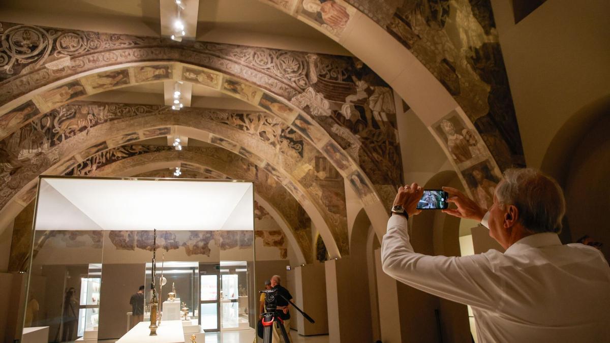 Un hombre fotografía las pinturas murales del Monasterio de Sijena expuestas en el Museu Nacional d’Art de Catalunya (MNAC)