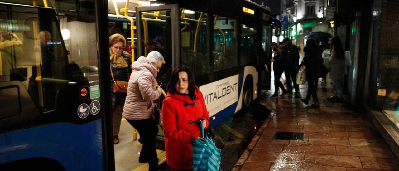 Tres mujeres, anoche, bajando de un autobús urbano en el centro de la ciudad.