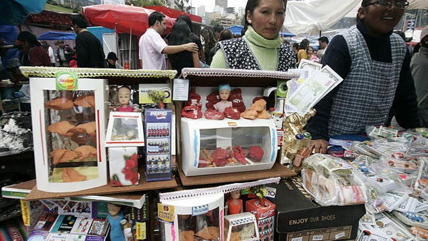 Dos mujeres venden miniaturas en La Paz (Bolivia), durante la inauguracion de la Feria de la Alasita, que por tradición se celebra en esta fecha a las 12 del día hora local, y que este año se realizó en medio del auto de buen gobierno, previo al referendo constitucional de este domingo. Durante la feria los asistentes compran miniaturas que luego bendicen con la esperanza de que se conviertan en realidad.