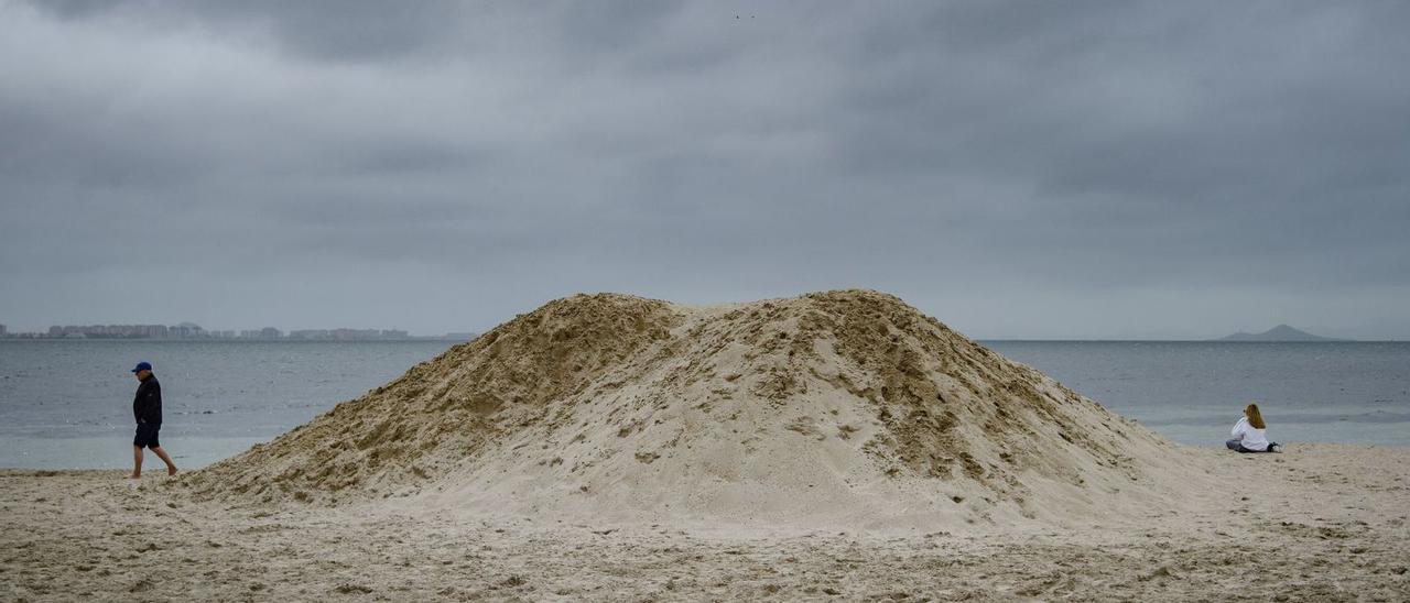 Dos personas, ayer, junto a un montículo de arena en la playa Castillico de San Javier.