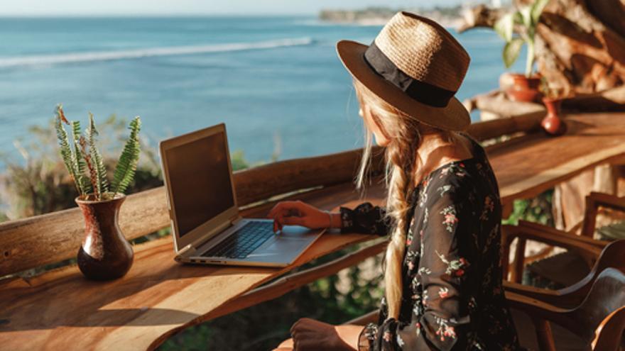 Una mujer consulta su portátil en su lugar de vacaciones.