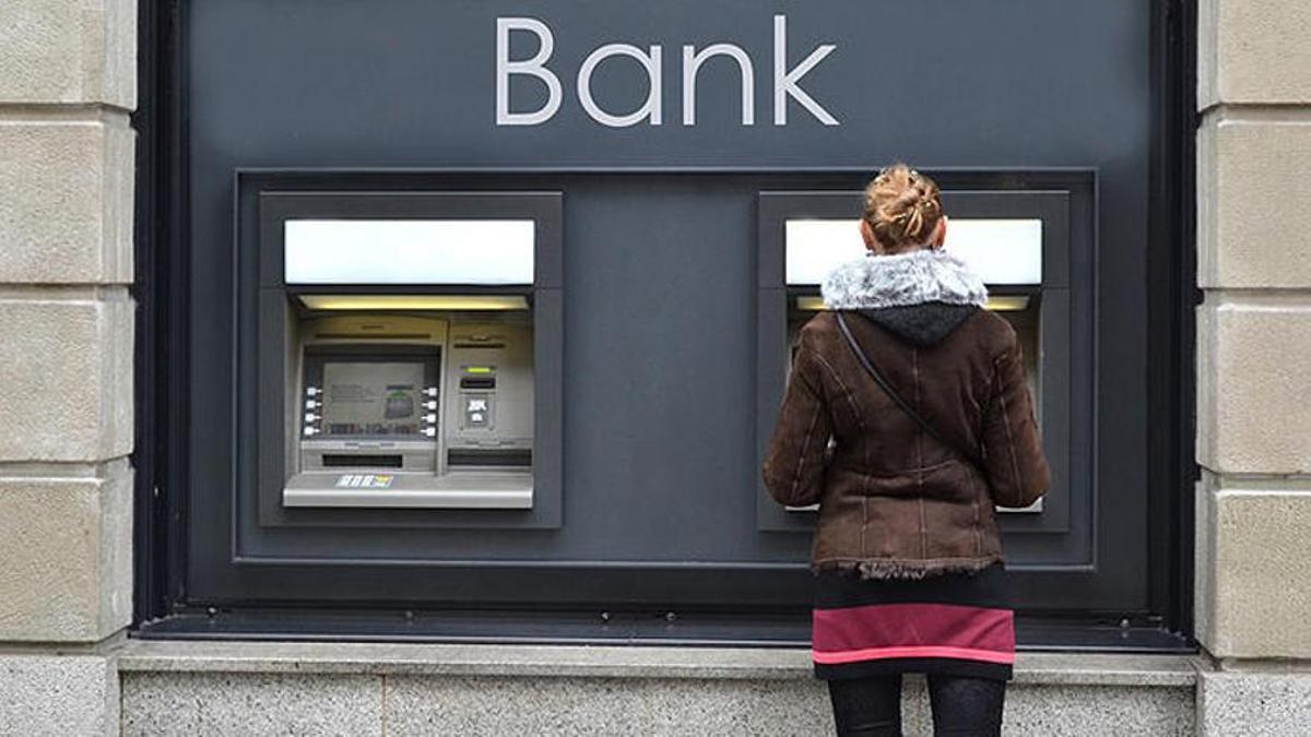 Una mujer saca dinero de un cajero automático.