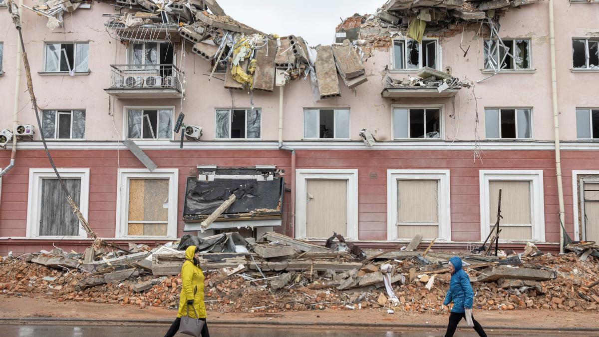 Dos personas caminan frente a un edificio bombardeado en Chernígov.