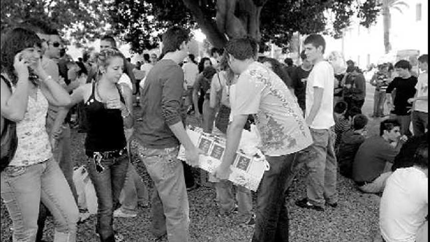 Dos jóvenes llevando una caja de tetrabrick, en plena fiesta universitaria