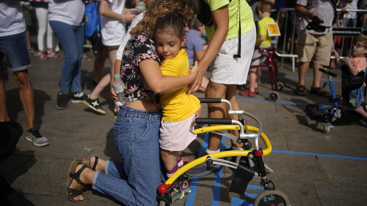 La pequeña Emma Joana es felicitada por su madre al finalizar la cursa adaptada para niños con discapacidades.