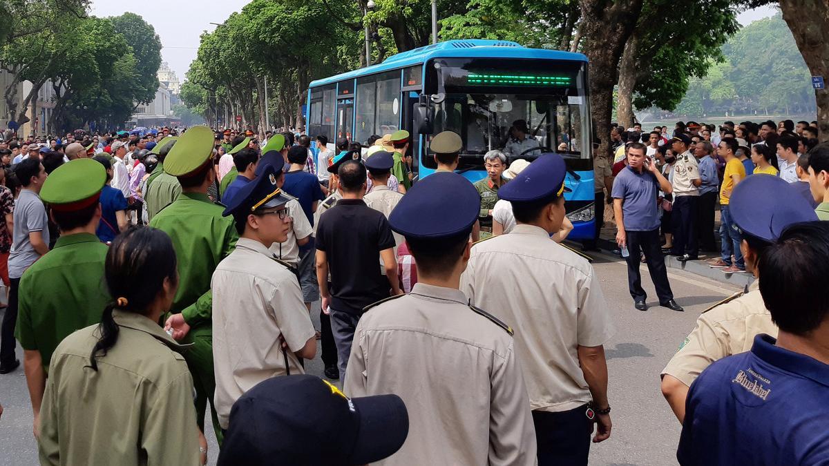 Police stand around a bus after they detained protesters during a demonstration against a draft law on the Special Economic Zone in Hanoi, Vietnam